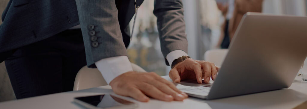 Modern business professional working on a laptop at a conference table.