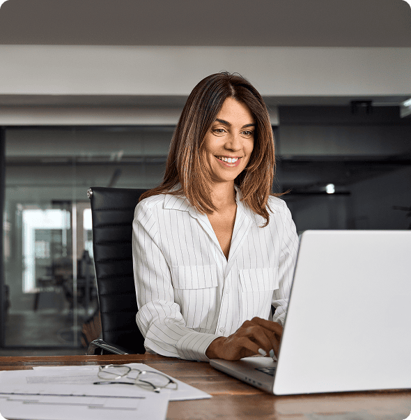 Professional woman working on a laptop in an office setting.