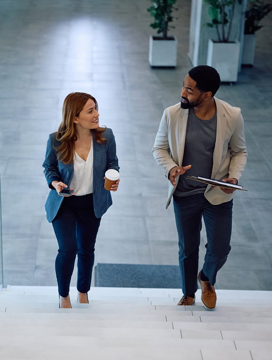 Business professionals walking and talking in modern office building.