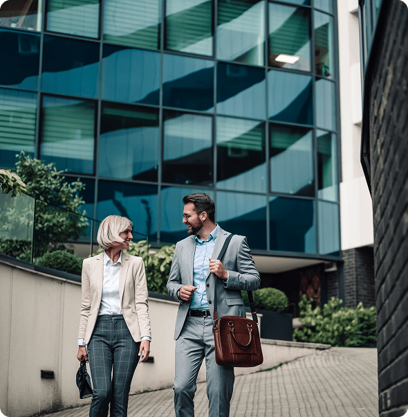 Business professionals walking and talking outside modern office building.
